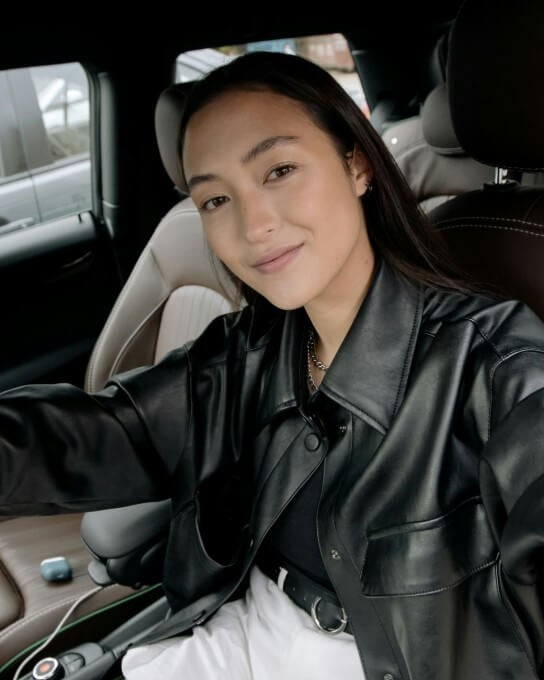 a woman in the black leathered jacket sitting in the car