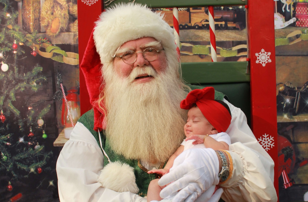 A Santa Claus holding a cute newborn
