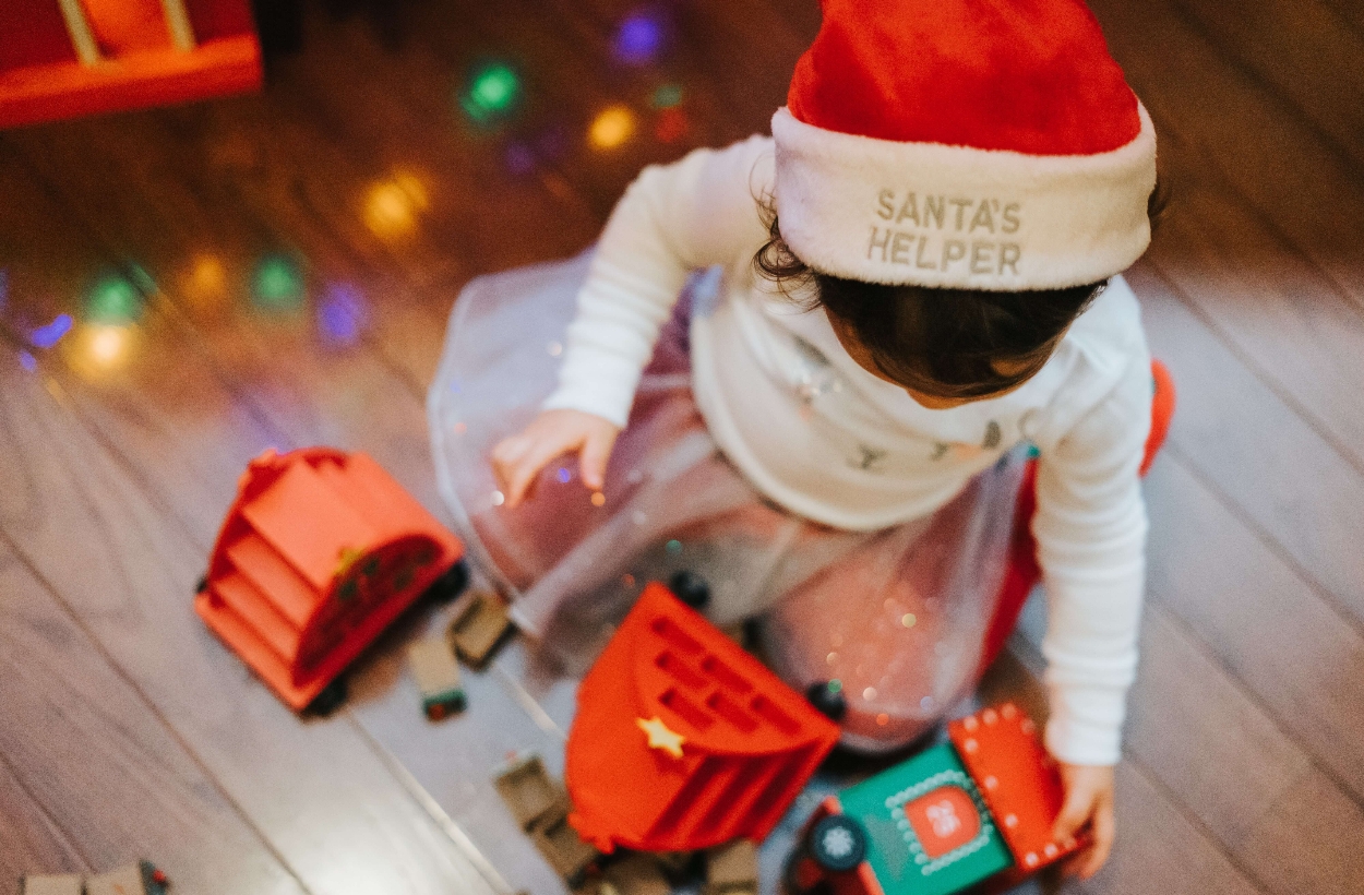 A baby wearing a santa hat playing with toys