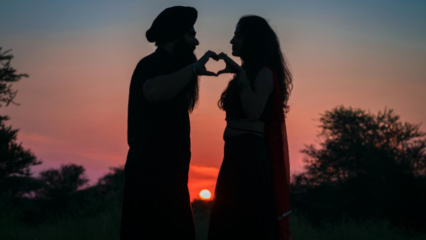A couple is silhouetted against the sunset