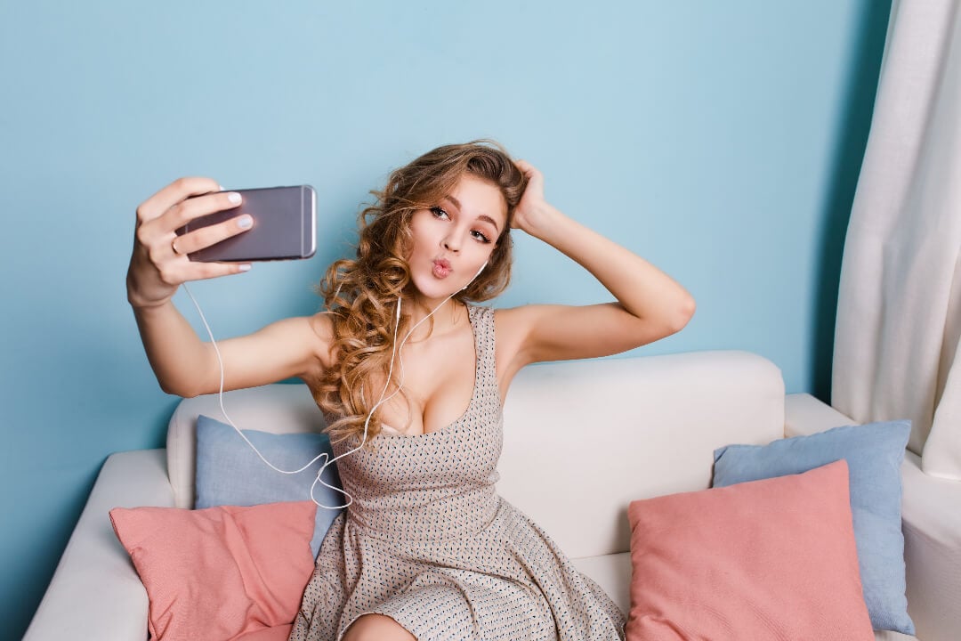 A girl with curly hair is taking a selfie on the sofa