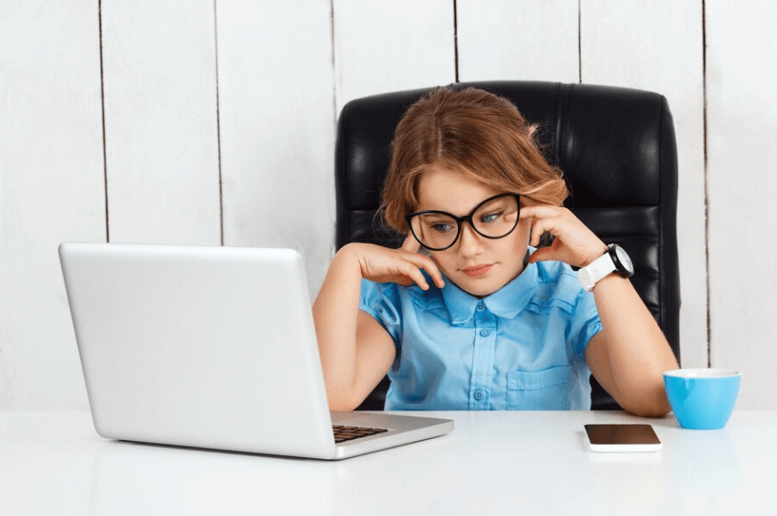 A little girl in glasses is looking at a computer screen