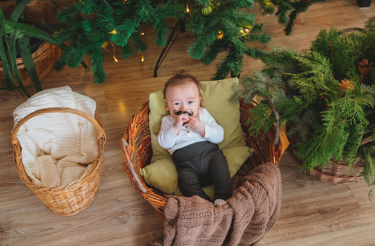 A lovely baby wearing a beard sticker sitting in a basket