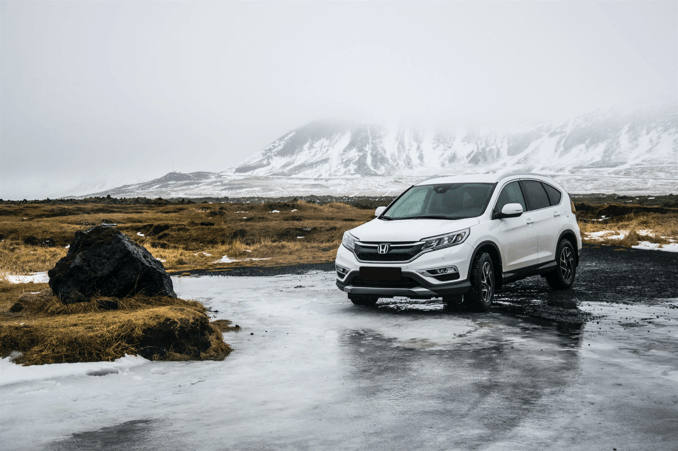 A white SUV at the foot of the snow mountain