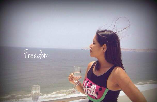 A woman by the sea holding a glass with Freedom text on it