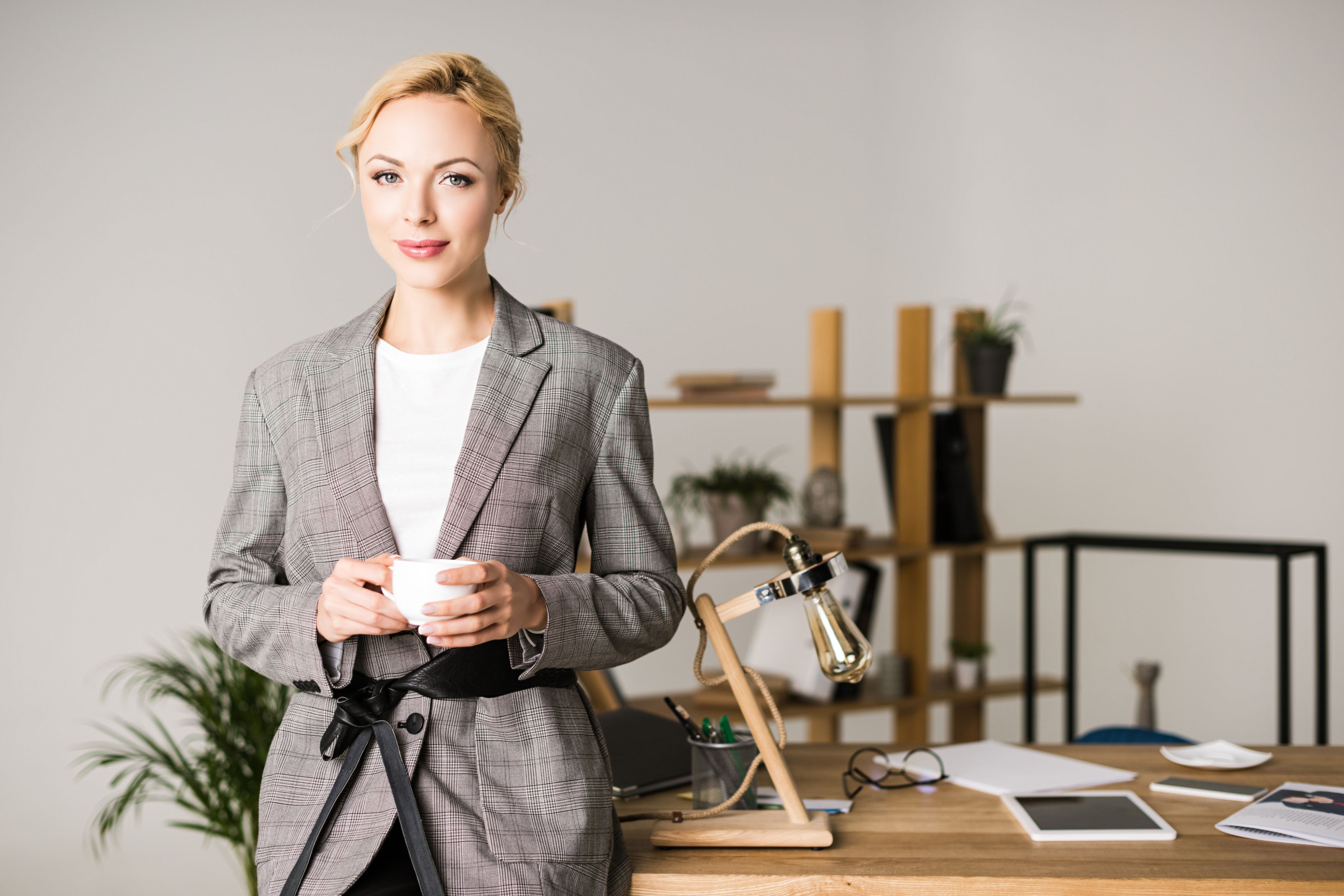 A woman in a plaid suit is holding a cap in the office