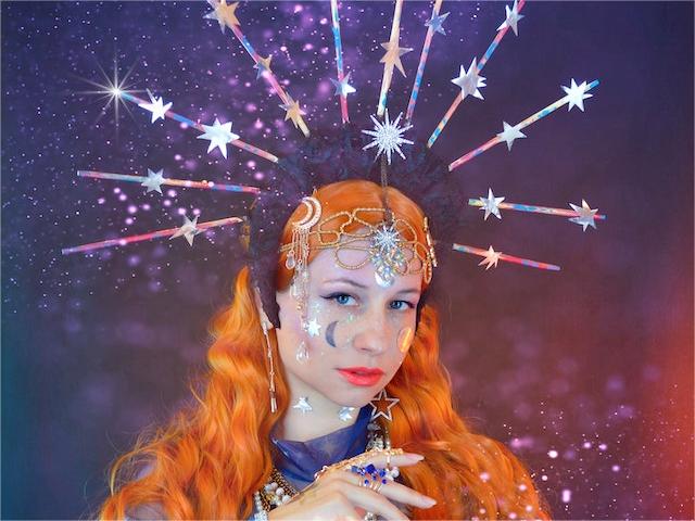 A woman with orange hair wearing moon witch makeup