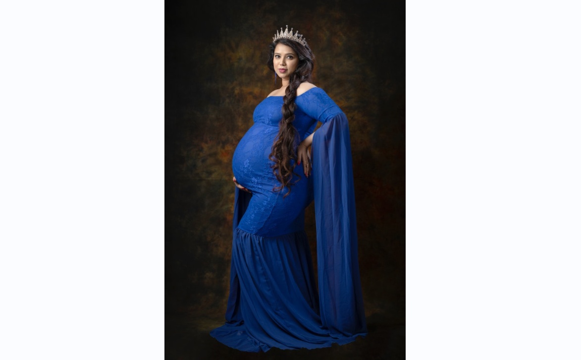 The pregnant princess wore a blue dress and crown