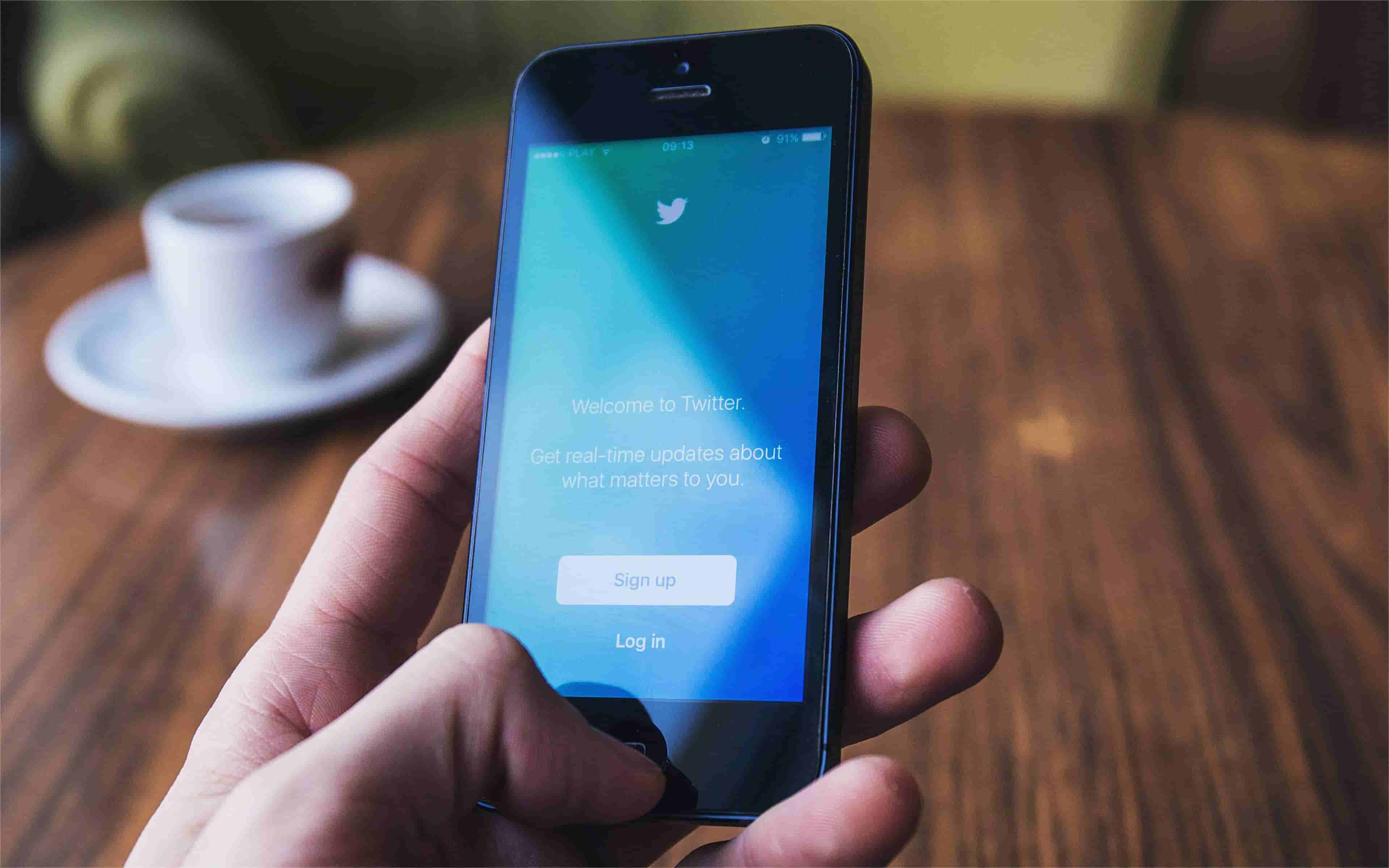 The phone shows Twitter login page.