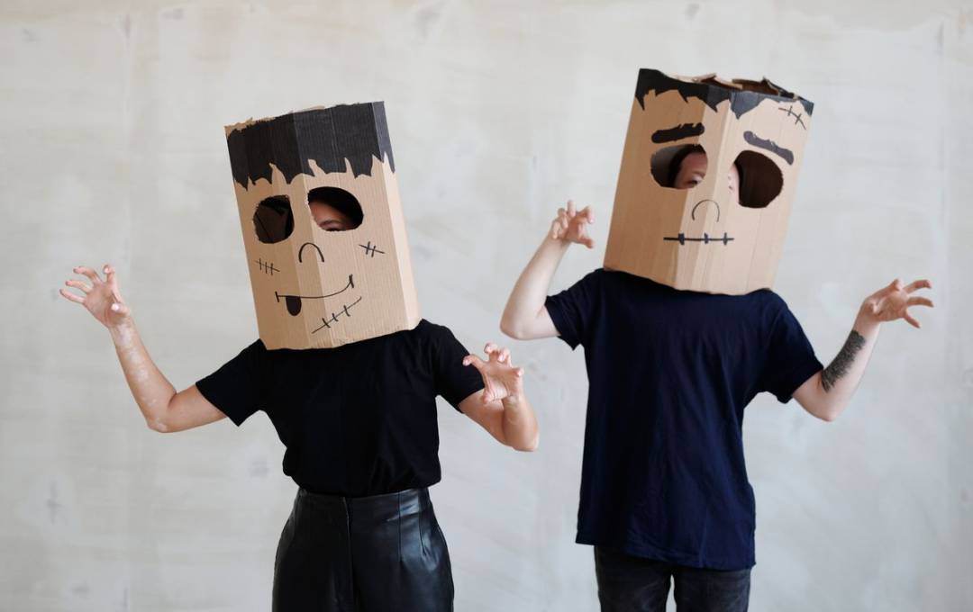 Two people wearing easy cardboard headgear pretend to be Halloween monsters