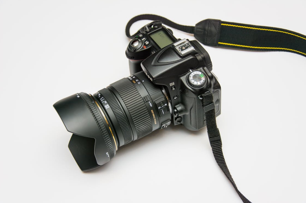 a balck dslr camera on the white surface