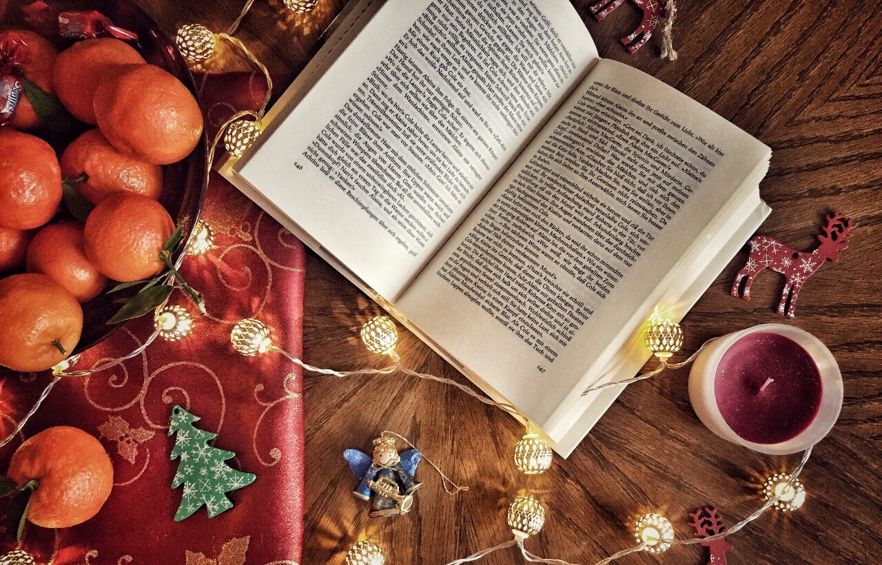 a book and oranges and Christmas decorations on the table