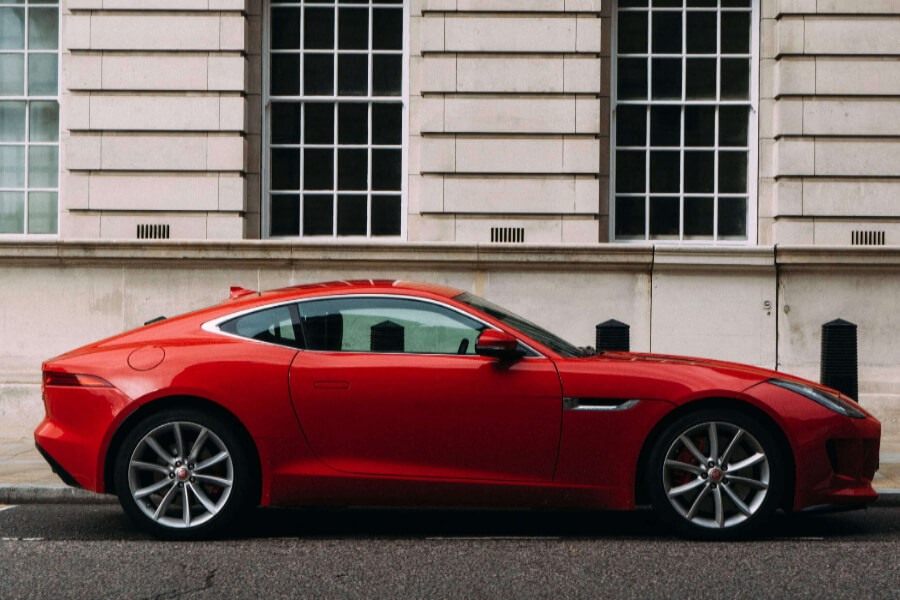 a red car with a white building as a background