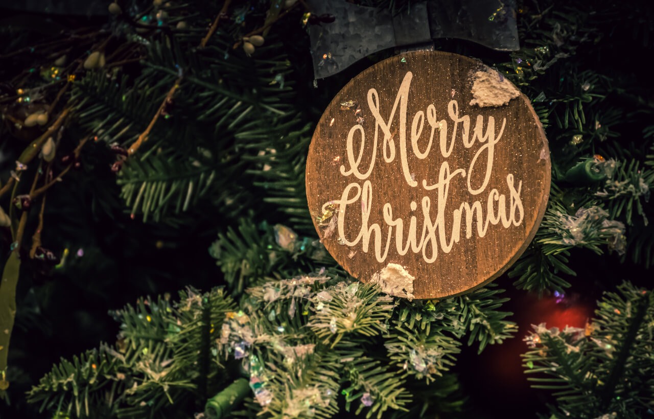 a brown wooden Christmas decor hangs on a Christmas tree