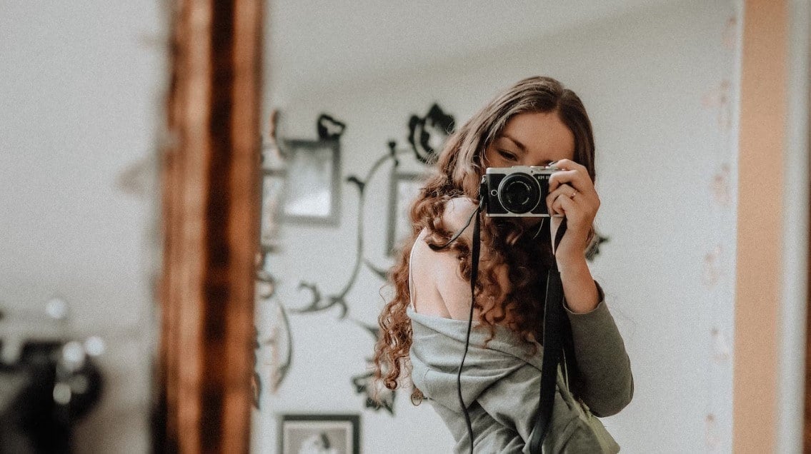 a girl hold a carema to take mirror selfies