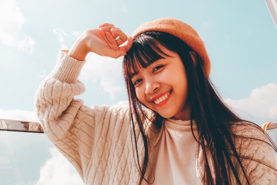 a girl wearing a pink hat with sky behind