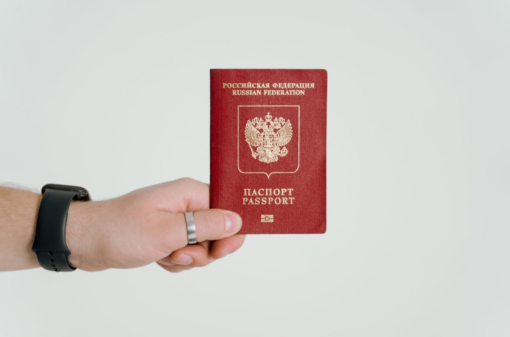 a hand holding a russian passport in a red color cover