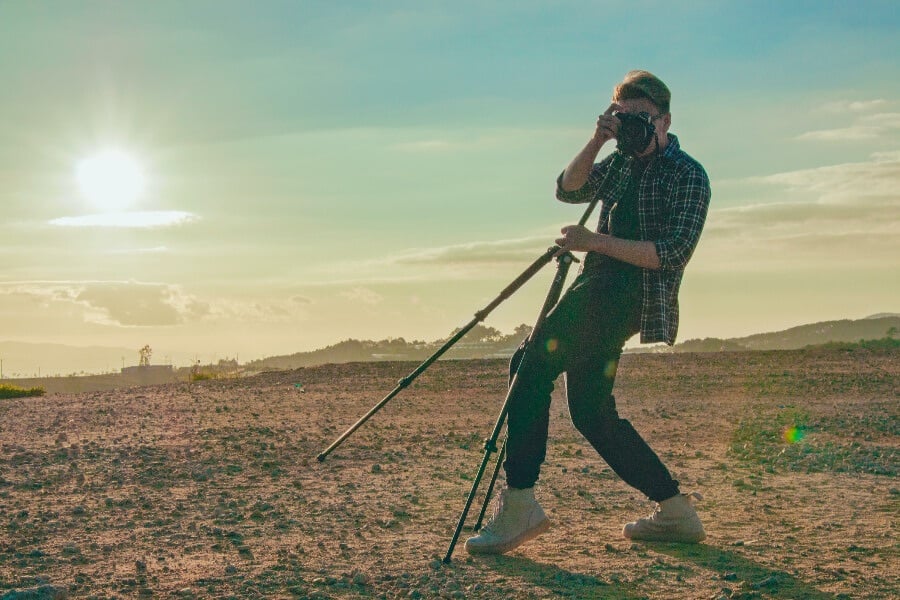 a man taking a photo with blue sky and sun behind