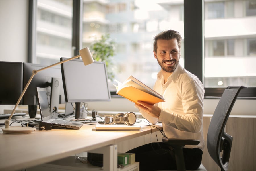 a man working in front of a computer with a notebook on its hands