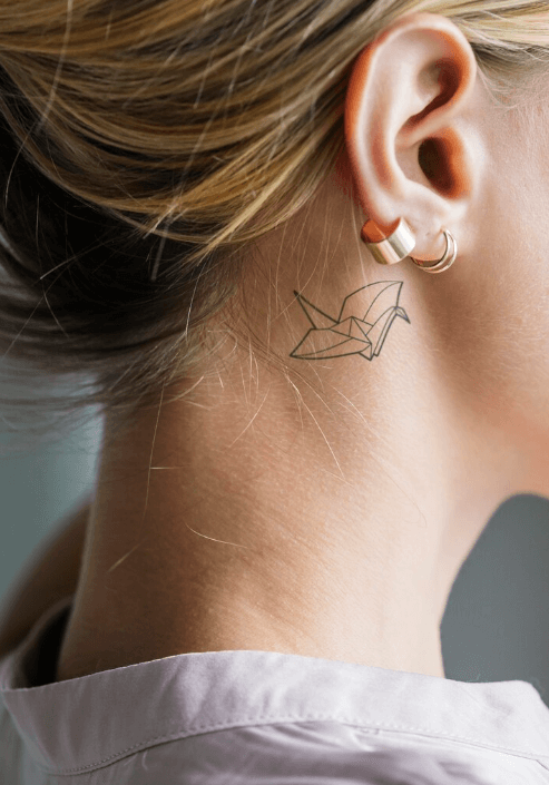 a paper airplane tattoo behind ear