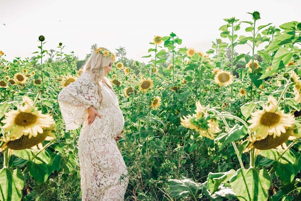 a pregnant woman stand in the sunflowers