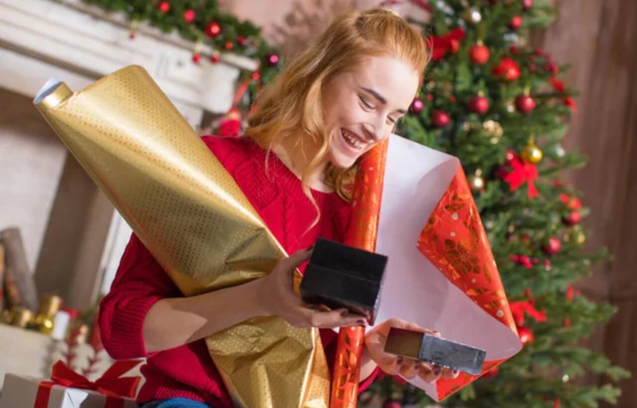 a smiling woman with Christmas gifts and wrapping papers