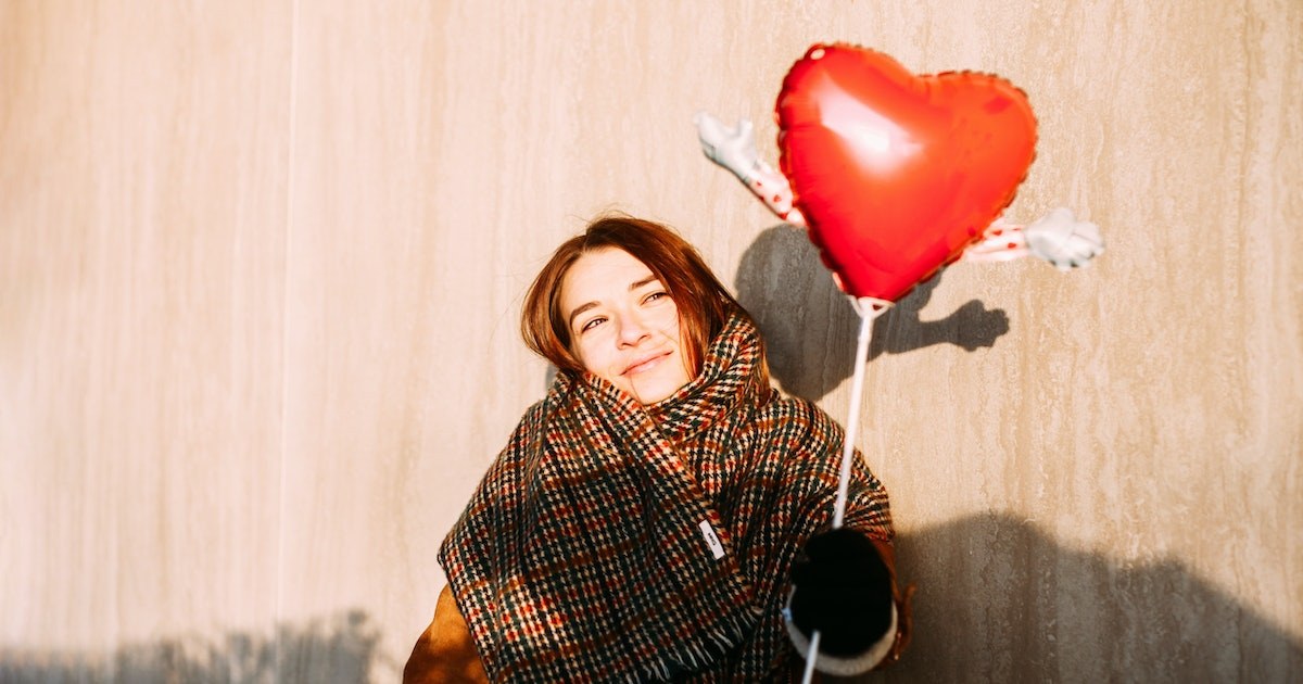 a solo valentine photoshoot of a female holding a red heart balloon