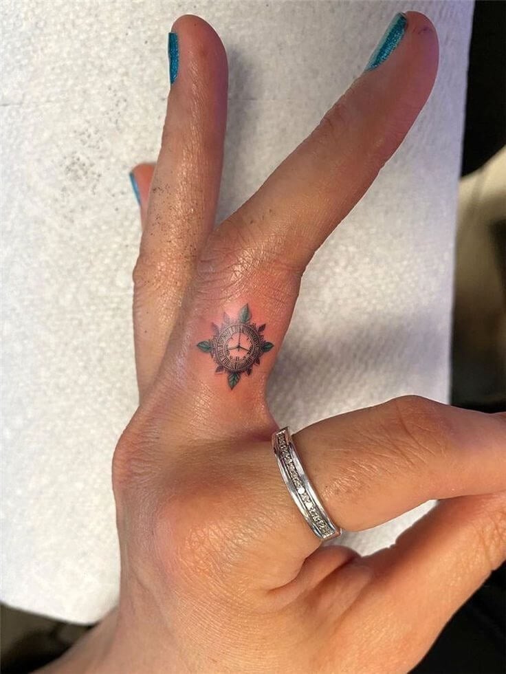 a vintage clock tattoo on the fingertip