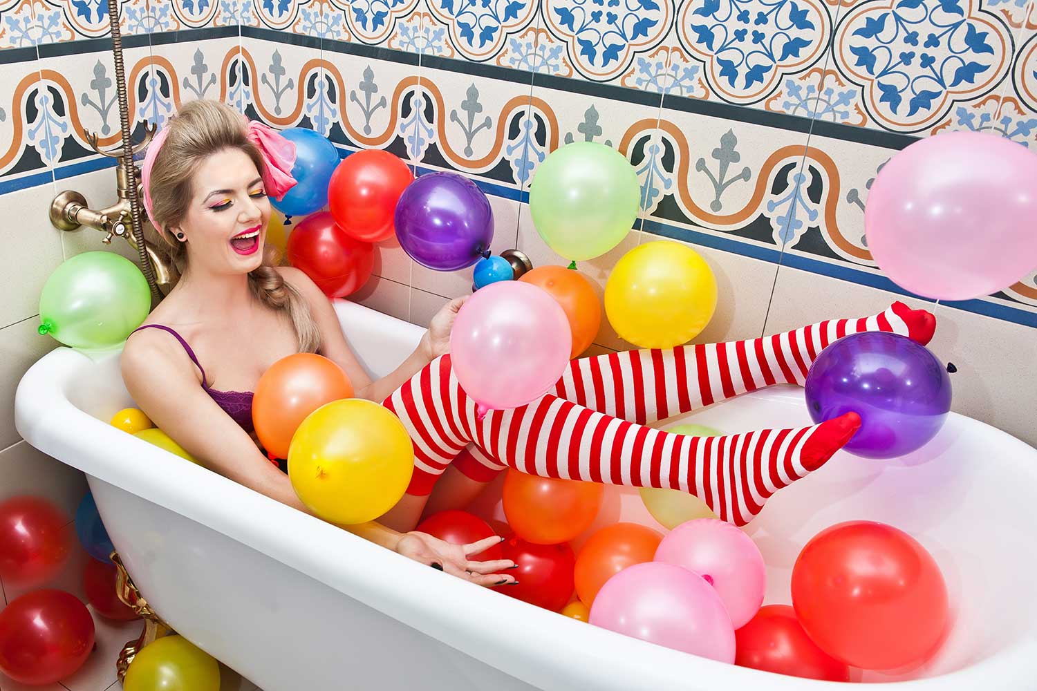 a woman lying and in the bathtub for her 30th birthday party with balloons