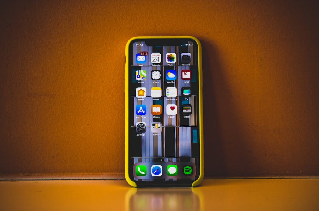 an iphone on the dark yellow desk