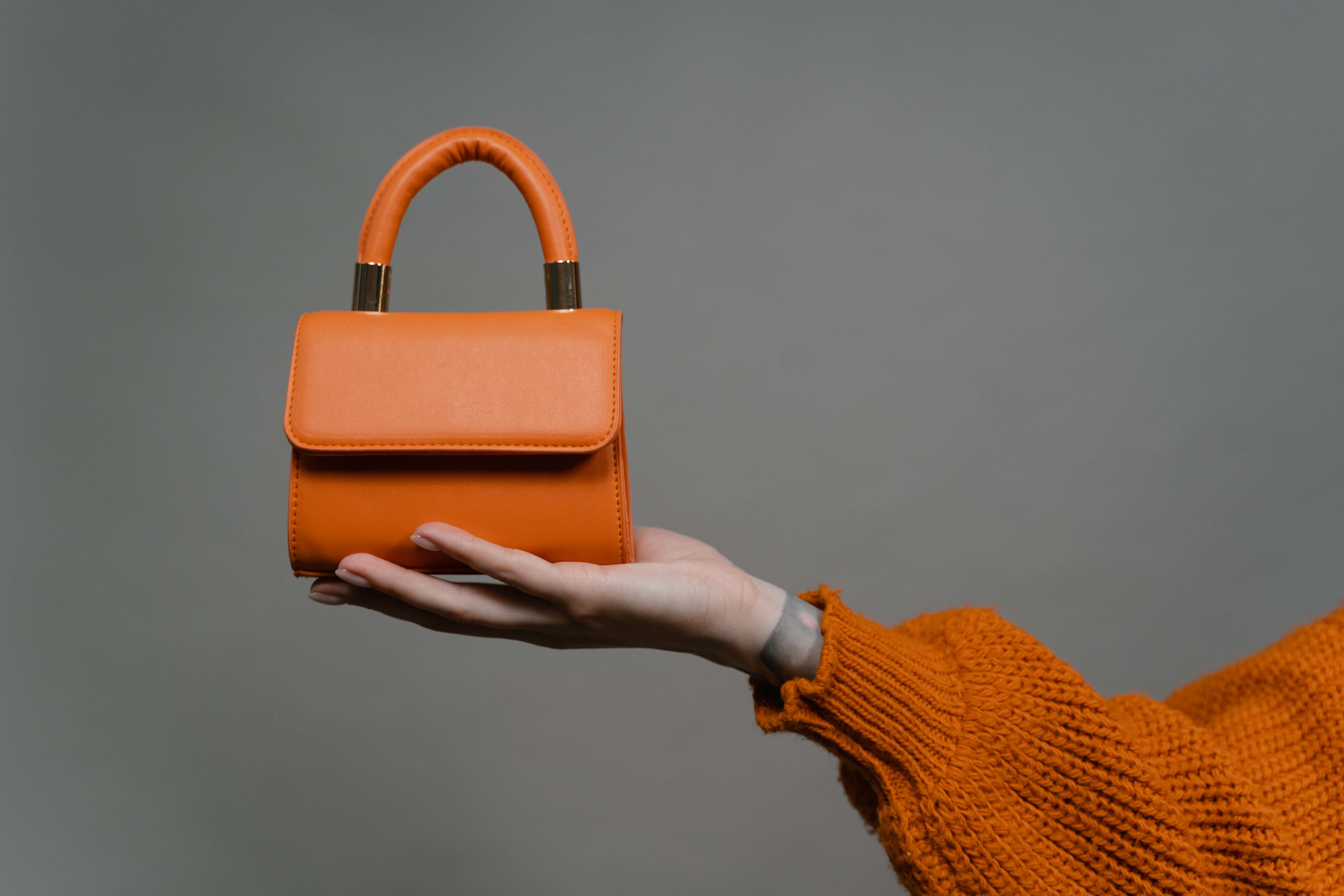 an orange bag on a woman's hand