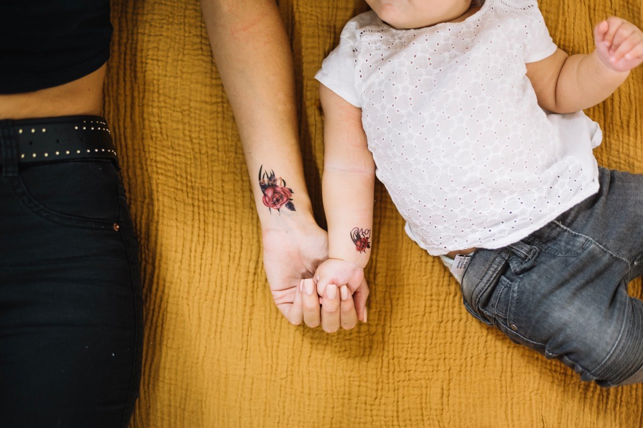 a woman and a baby with a rose family tattoo