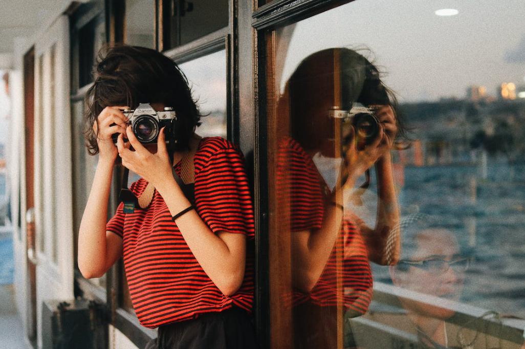 female in red shirt taking a picture using a camera