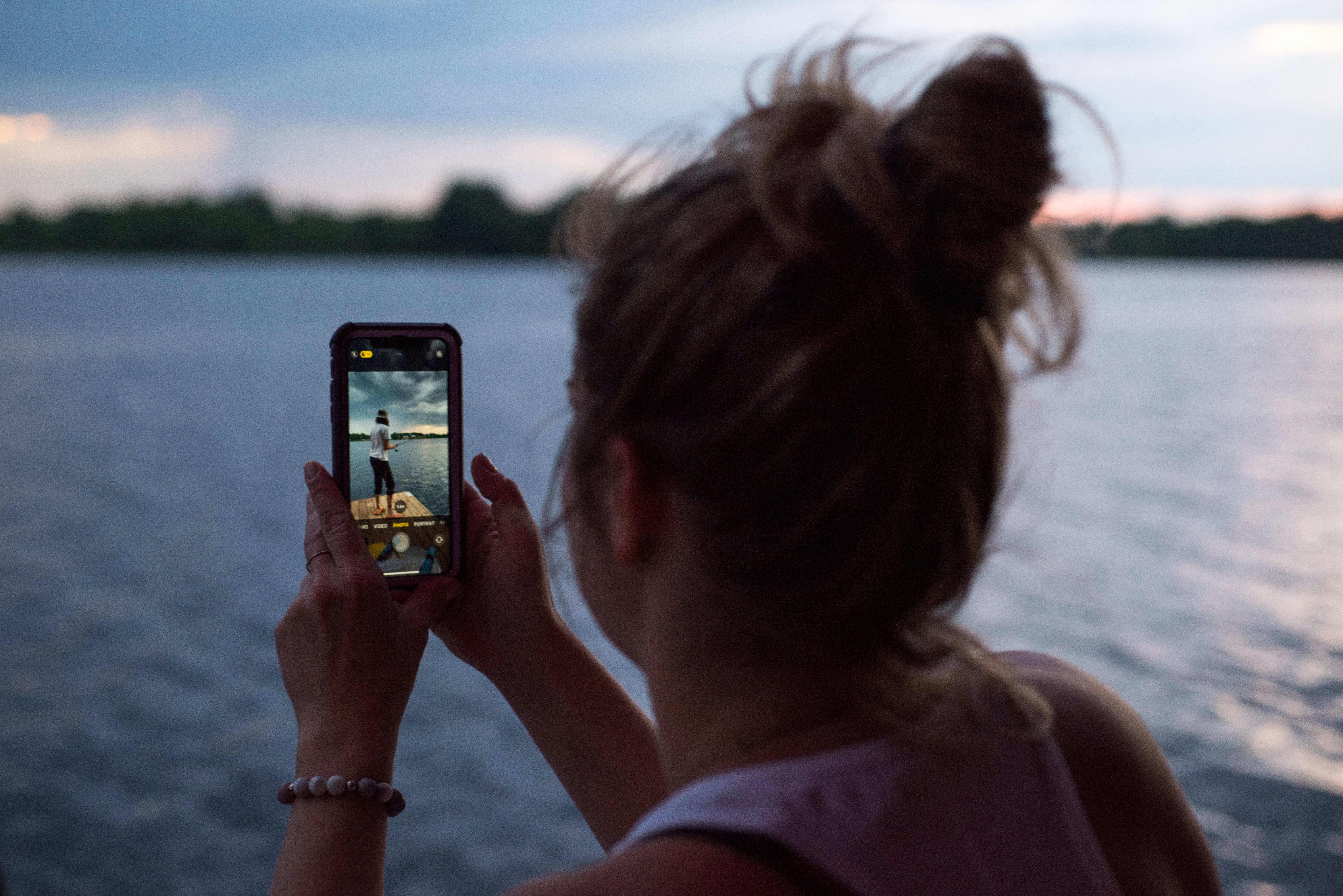 female taking pictures near the water on the phone