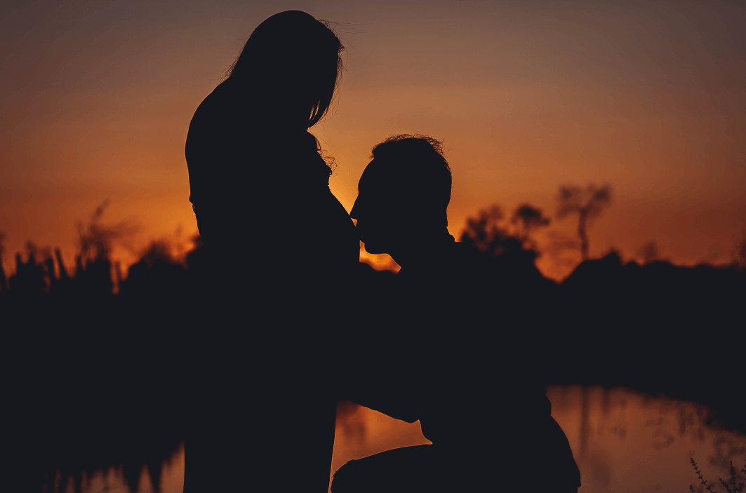 husband is kissing wife's belly with silhouette shooting