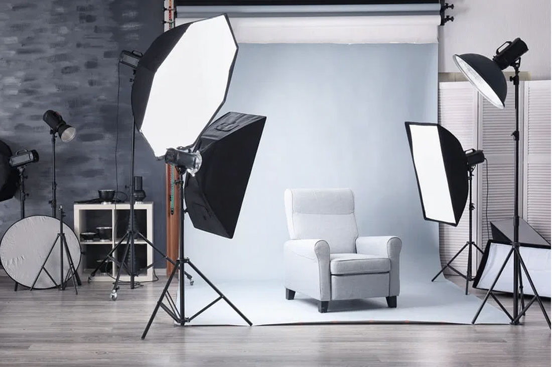lighting equipment and cameras and a sofa with a white backdrop