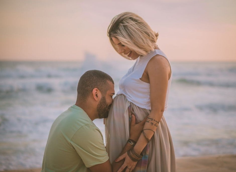a maternity photoshoot with husband by the sea