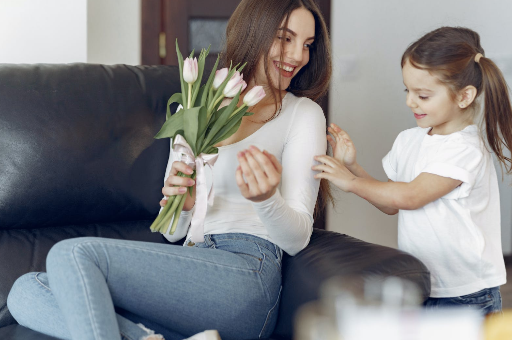 a mom looking at her daughter and holding a bouquet of tulips