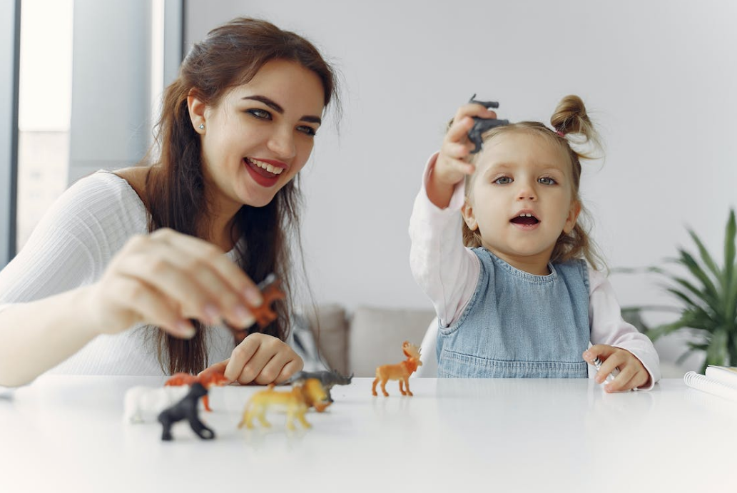 a mom plays with her baby and some prop toys on the white table