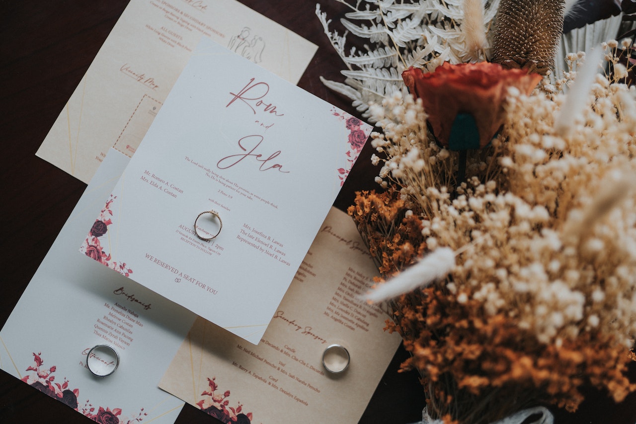 rings are on the wedding invitation card, and flowers are right side of the cards