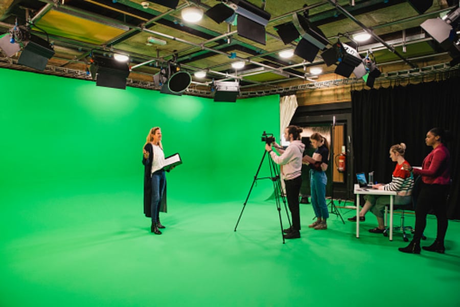 several people shooting a woman standing with the green screen