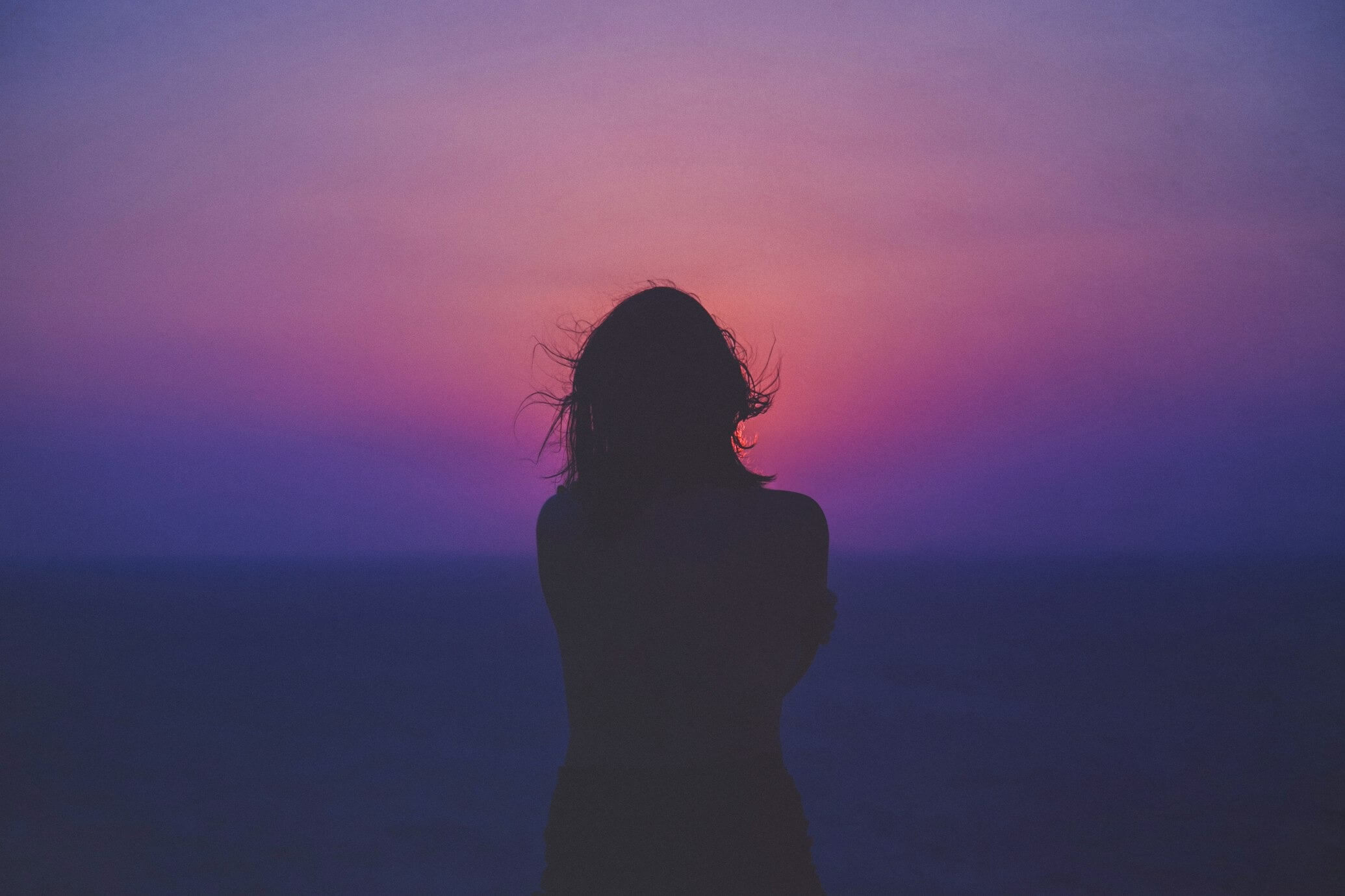 woman silhouette under pink and purple sky