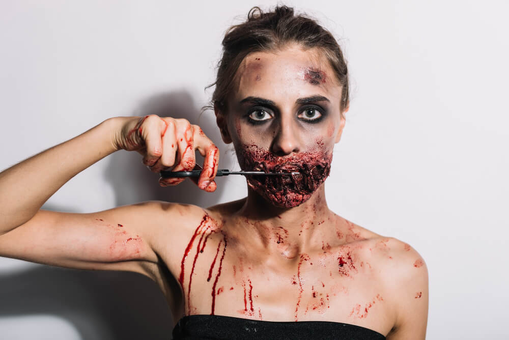 spooky female cutting stitched mouth with scissors