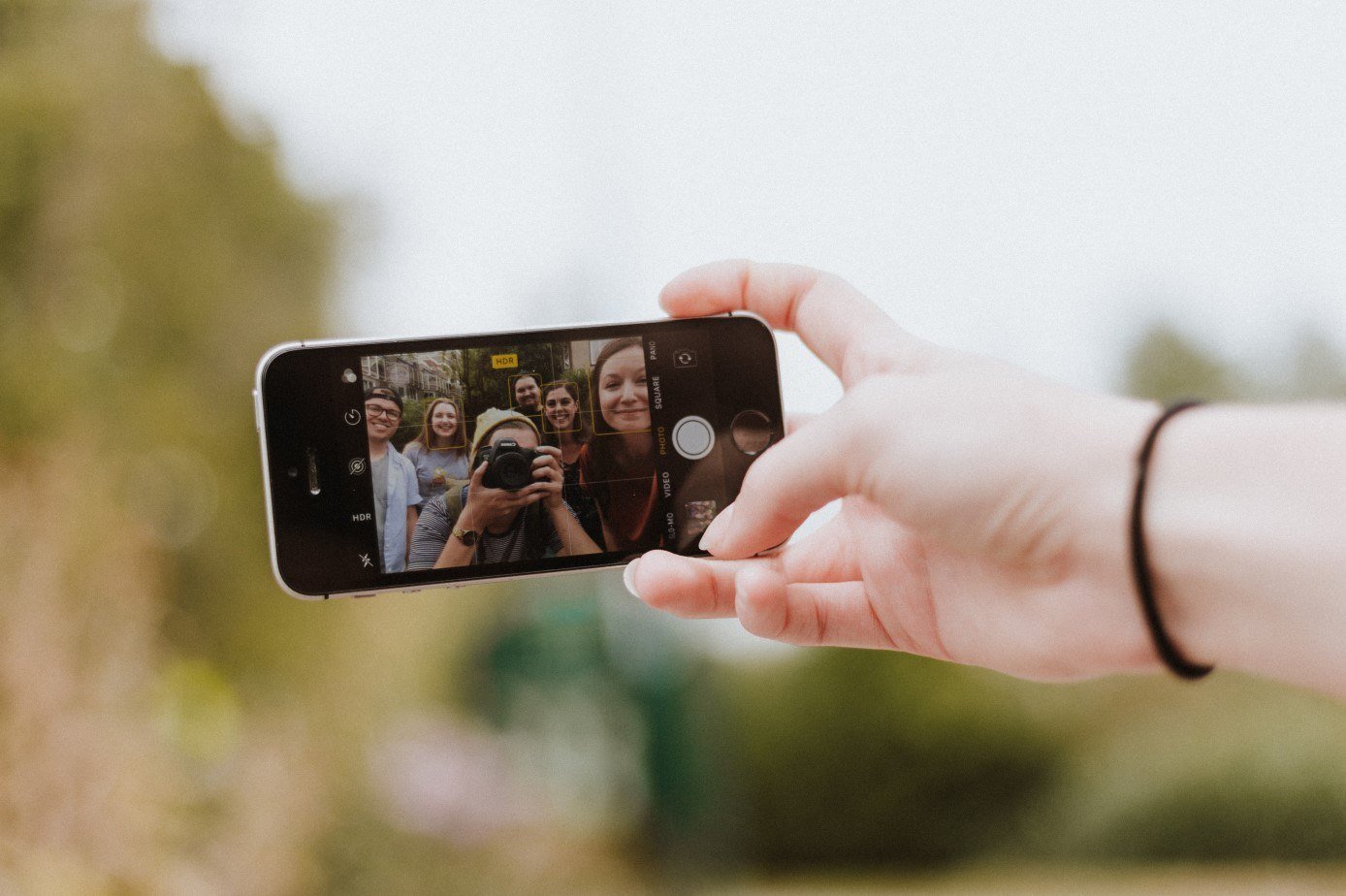 a hand is holding a phone to take selfie with friends