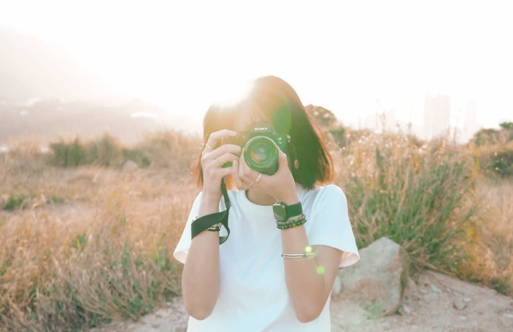 a woman takes photos in the grassland