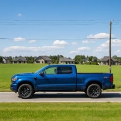A small blue truck on a town road thumbnail