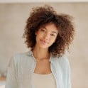 A thumbnail of a woman with curly hair wearing light colored clothing