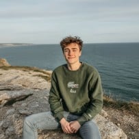 The thumbnail of a man in green pullover sitting by the sea
