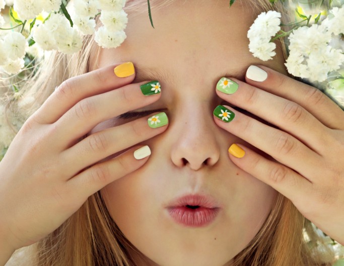 The little girl shows her nail art by covering her face with hands