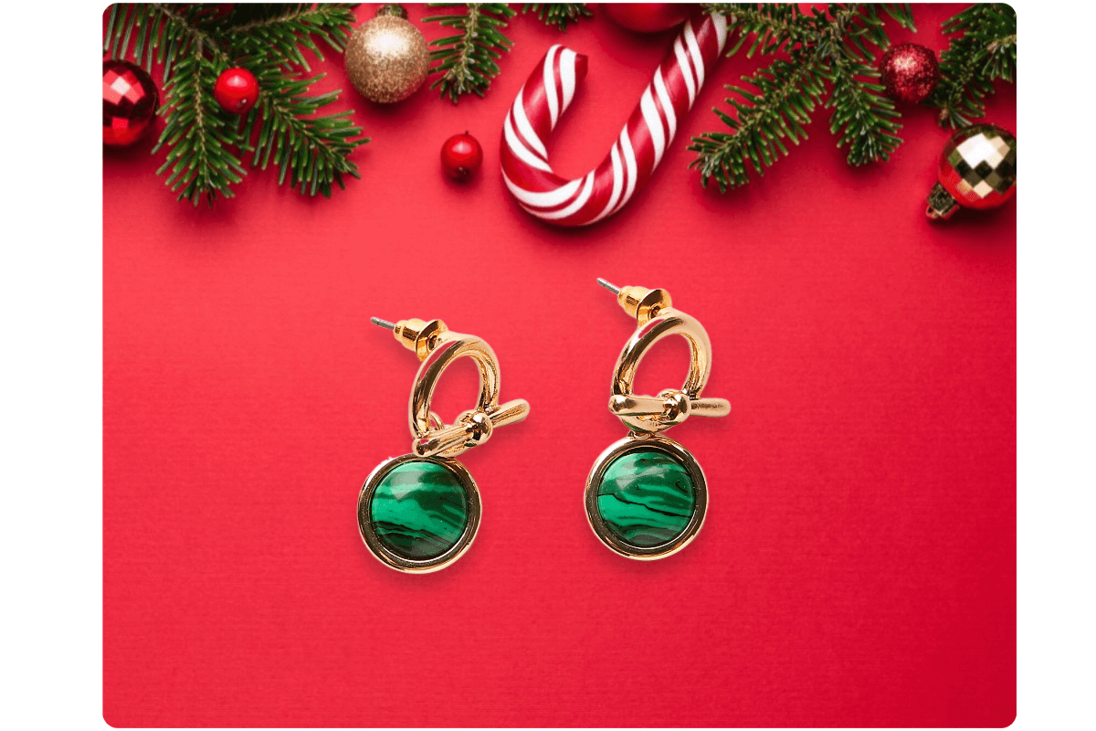 A pair of emerald earrings with a red christmas background